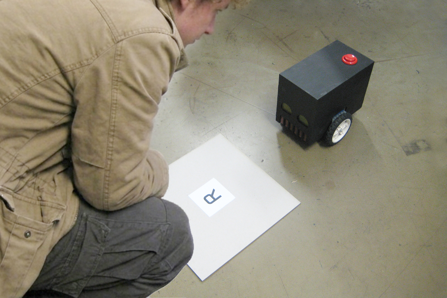 A person observes the finished, black-painted play robot at the playtesting.