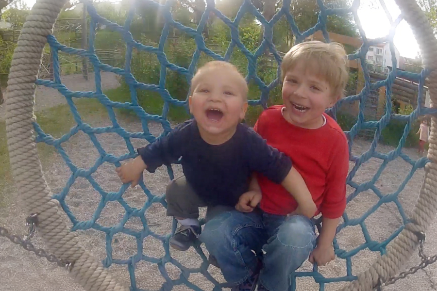 Perspective from a playground swing showing a father holding his toddler in his arms.
